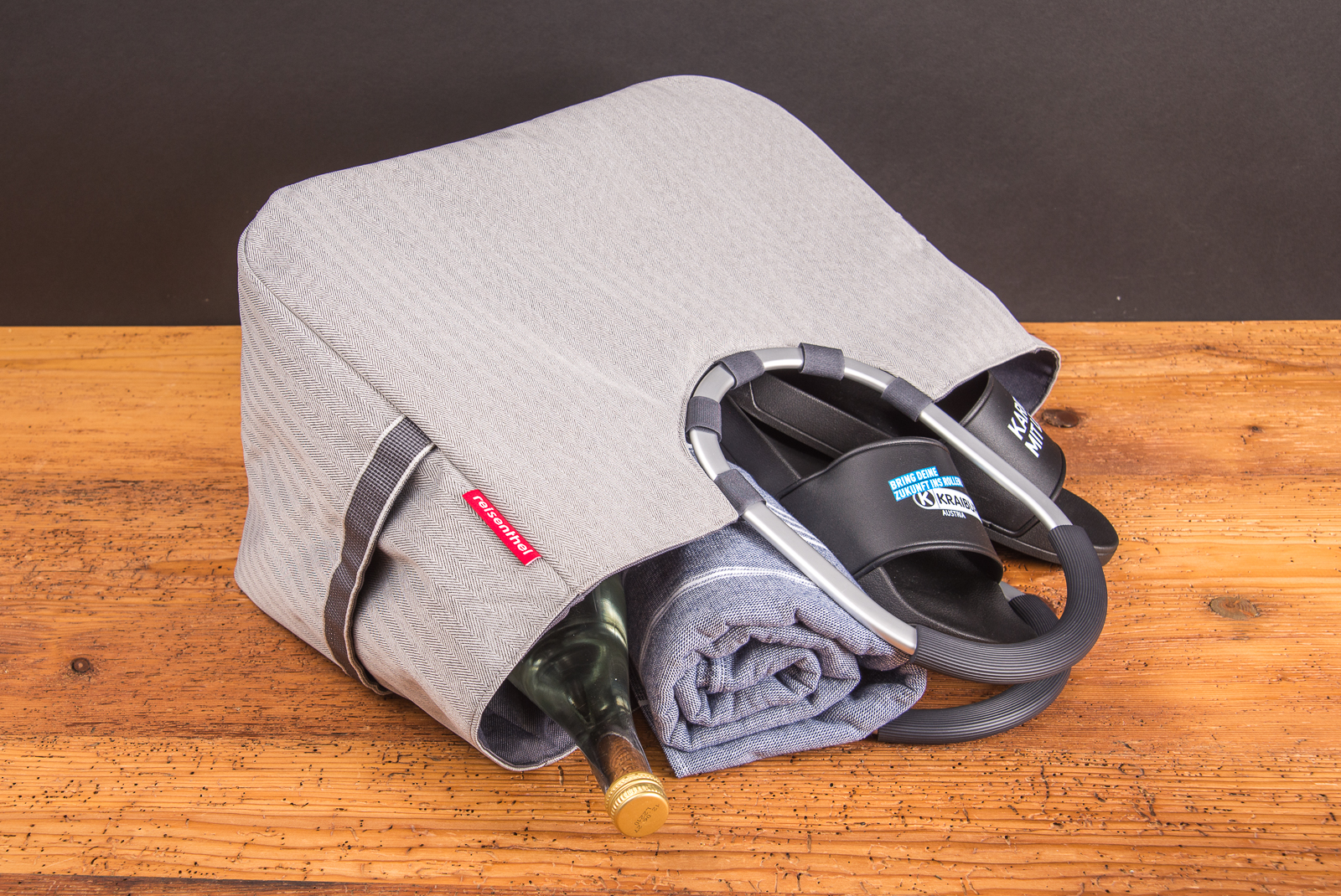 Reisenthel Einkaufstasche Dekor herringbone grey mit Flasche, Handtuch und Sandalen &ndash; praktischer Shopper mit stabilem Griff und viel Stauraum.