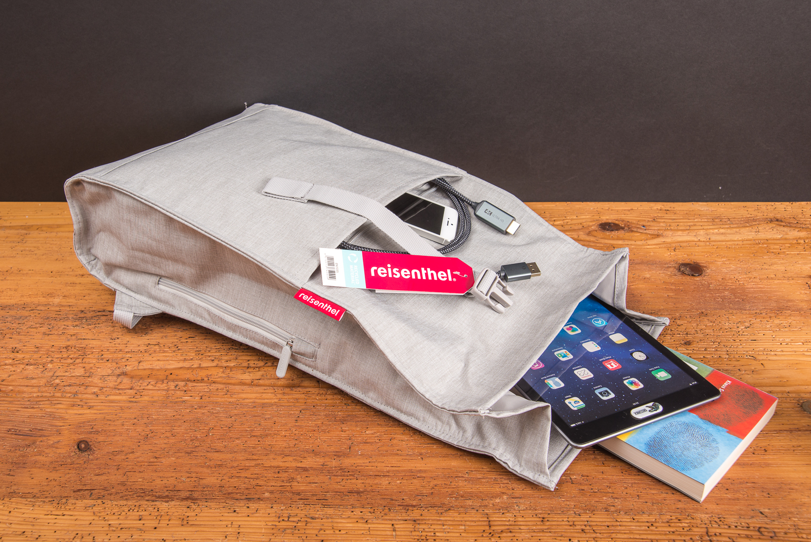 Reisenthel Urban Rolltop Rucksack Twist Silver in Grau, ge&ouml;ffnet mit Tablet, Smartphone und Zubeh&ouml;r &ndash; moderner Laptoprucksack aus recyceltem Material als nachhaltiges Werbegeschenk f&uuml;r Mitarbeiter und Kunden.