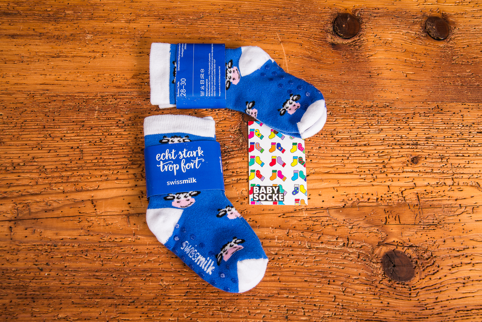Individuell gestaltete Babysocken als pers&ouml;nliches Geschenk zur Geburt mit Ihrem Firmenlogo. Ein Paar Babysocken in blau mit wei&szlig;en Zehen und Fersen mit lustigen Kuhmotiv. Mit Rutschnoppen.