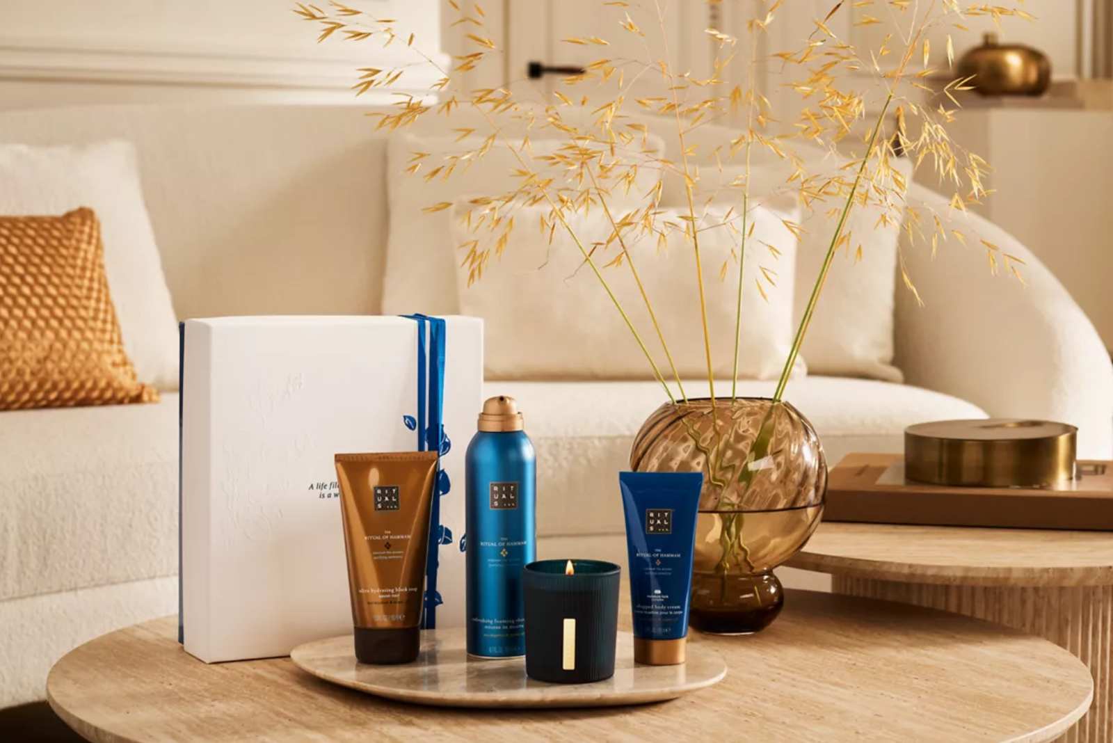 Rituals Hammam Gift Set M mit Pflegeprodukten und Kerze als hochwertiges Wellness-Mitarbeitergeschenk im Wohnzimmerambiente.