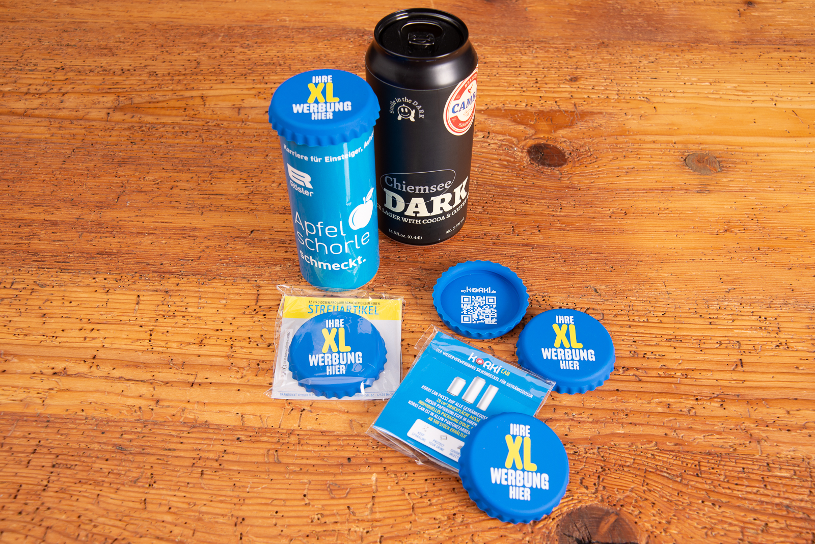 XL Korki Can Silikon-Dosendeckel als wiederverwendbares Werbegeschenk, mehrere blaue XL-Dosendeckel mit Dosen auf Holztisch.