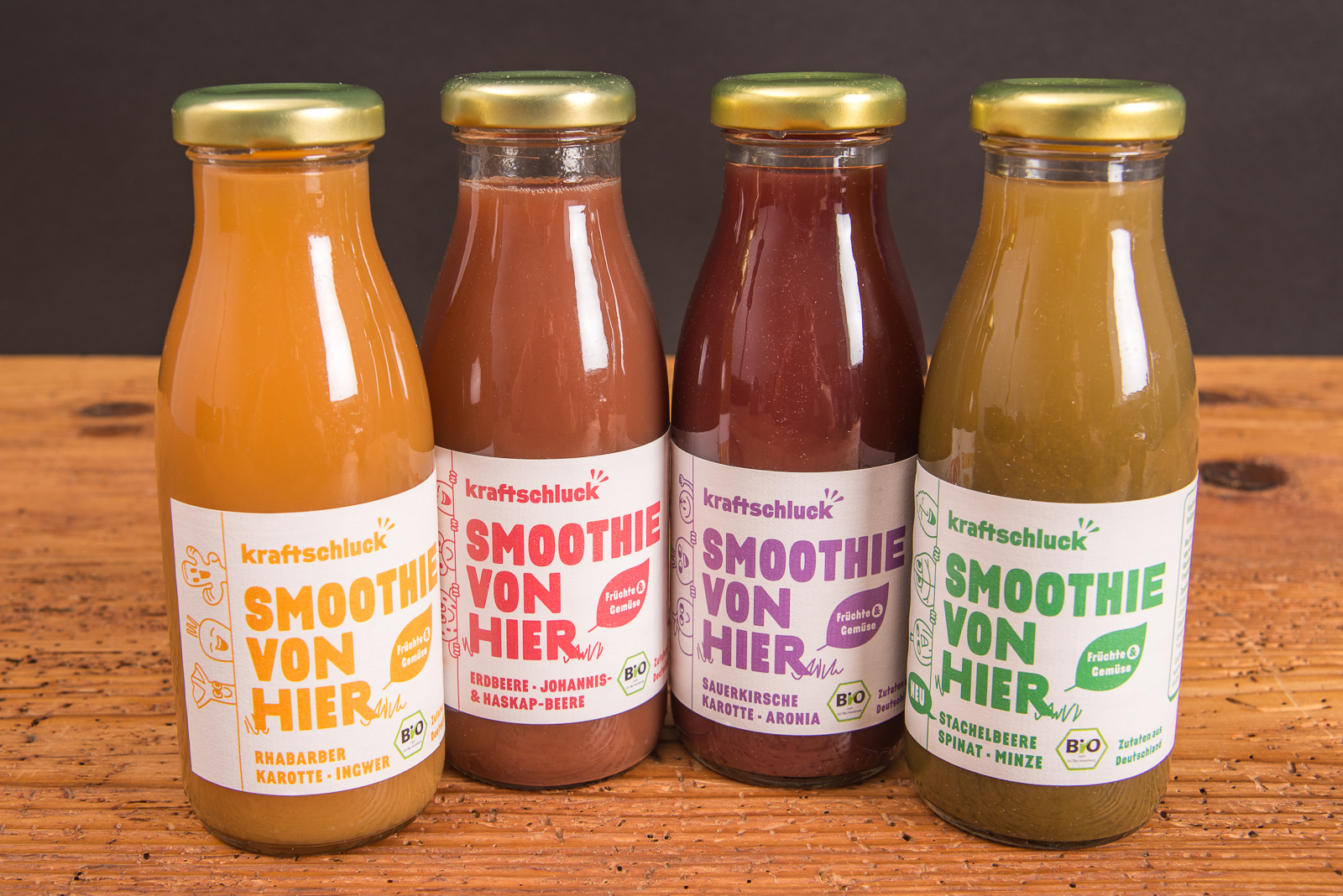 Kraftschluck Bio Smoothies in verschiedenen Sorten auf Holztisch &ndash; nachhaltiger Smoothie Werbeartikel aus Bayern als gesundes Werbegeschenk mit Logo