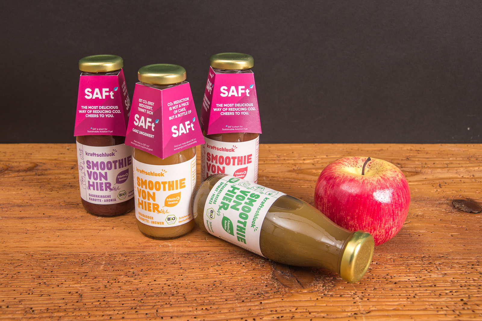 Kraftschluck Smoothie Flaschen mit pinker Werbebanderole und Apfel &ndash; Bio Smoothie als Werbegeschenk mit Logo f&uuml;r Messen und Events