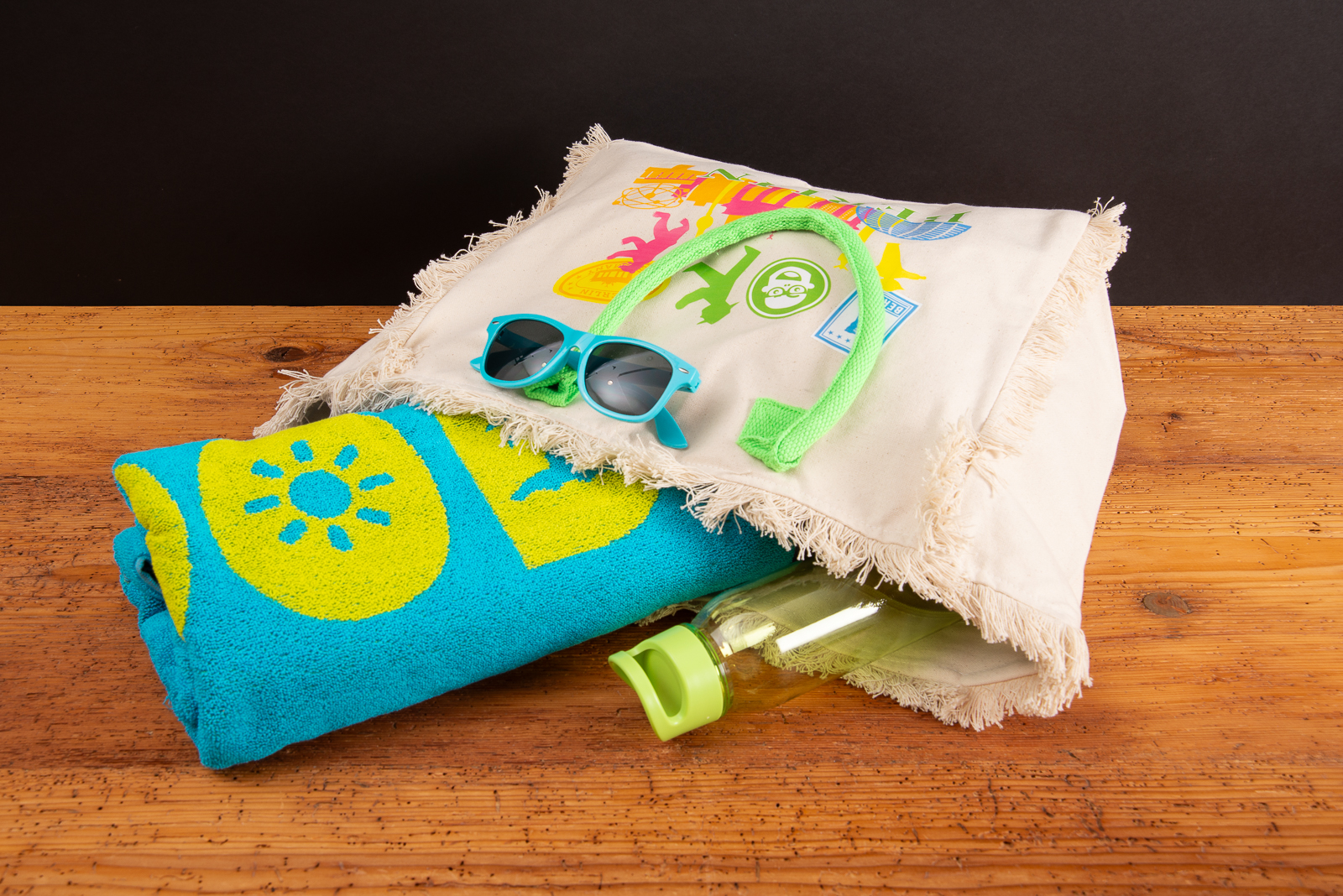 Strandtasche Lola mit Reissverschluss &ndash; gef&uuml;llte Strandtasche mit Handtuch, Sonnenbrille und neonfarbenen Kordeln als Merchandising Geschenk. 