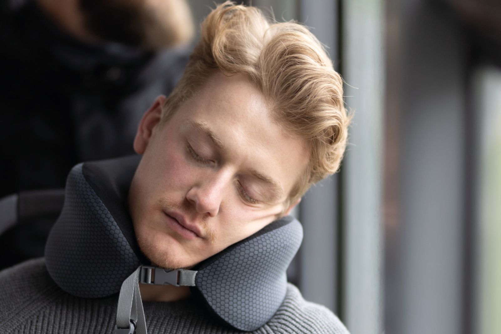 Anwendung des TROIKA Business Travel Pillow als Nackenkissen im Flugzeug zur Nackenentlastung