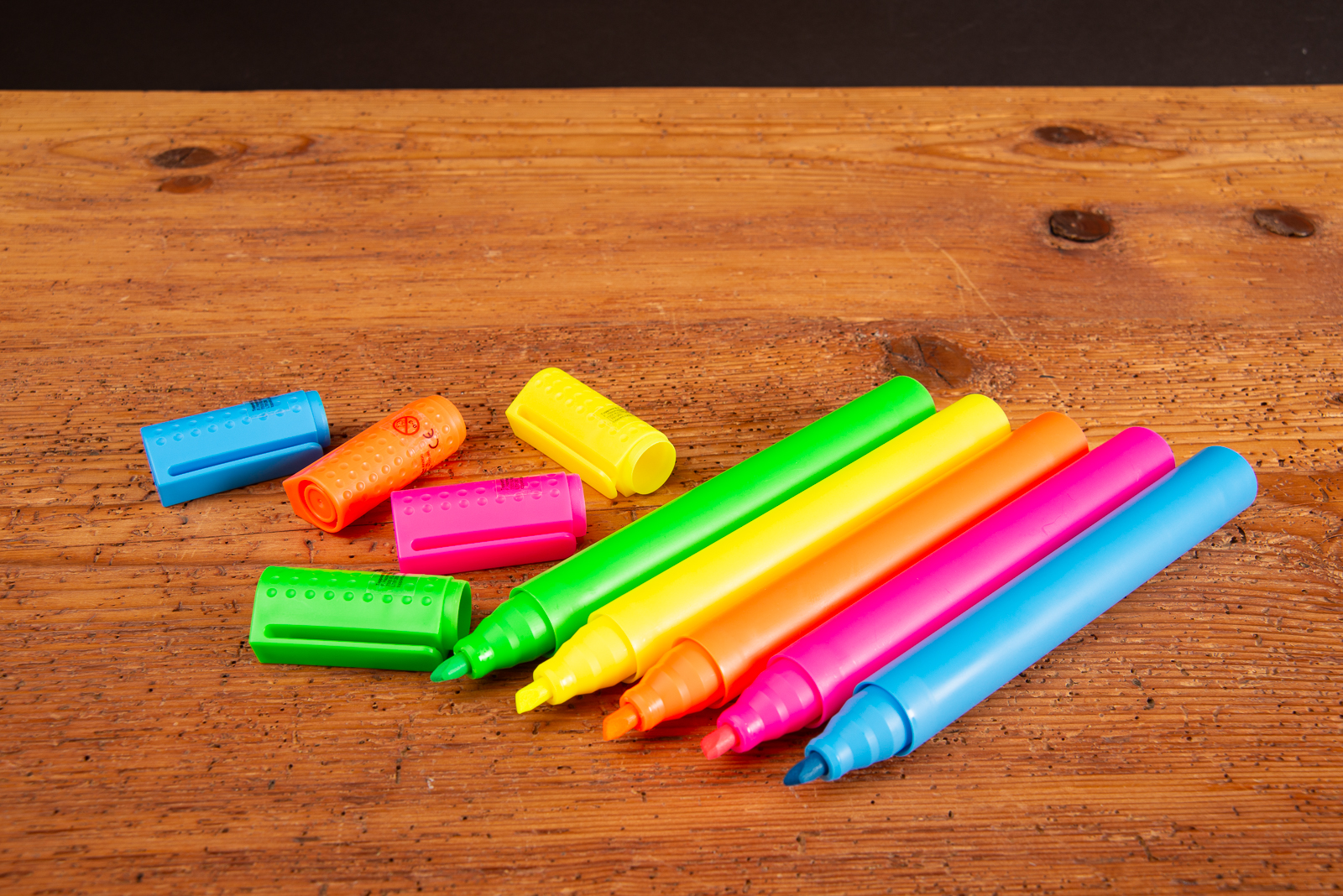 Ge&ouml;ffnete Jumbo Textmarker im XL-Format in leuchtenden Farben als Riechstifte auf Holztisch &ndash; kreative Giveaway-Idee f&uuml;r Messen und Bewerbermarketing mit gro&szlig;er Werbefl&auml;che und starkem Markenauftritt.