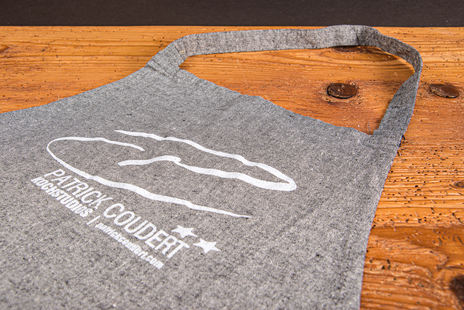 Sch&uuml;rze aus recyceltem Material mit Logo-Druck auf grauem Stoff &ndash; nachhaltige Kochsch&uuml;rze mit Logo f&uuml;r K&uuml;che und Grill