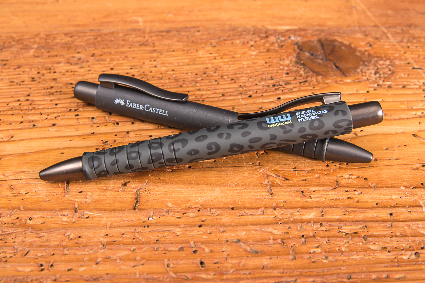 Faber-Castell Kugelschreiber Poly Ball mit Logo als nachhaltiger Werbeartikel auf Holzuntergrund &ndash; ergonomischer Kugelschreiber bedruckt f&uuml;r Unternehmen.