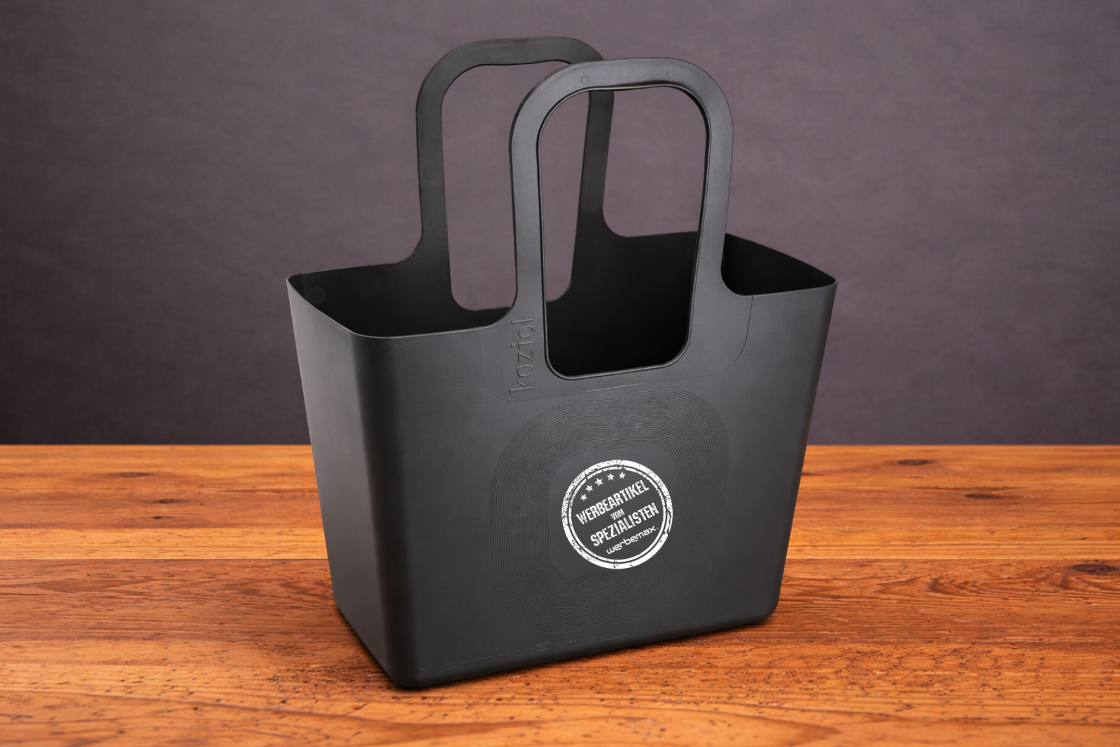 Koziol Tasche XL in Schwarz mit individuellem Logo als hochwertiger Werbeartikel auf Holztisch.