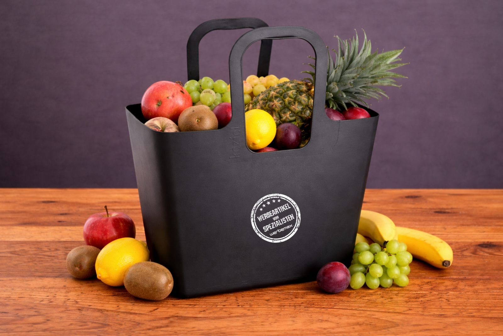Koziol Tasche XL in Schwarz gef&uuml;llt mit frischem Obst und dekorativem Arrangement als nachhaltiger Werbeartikel.