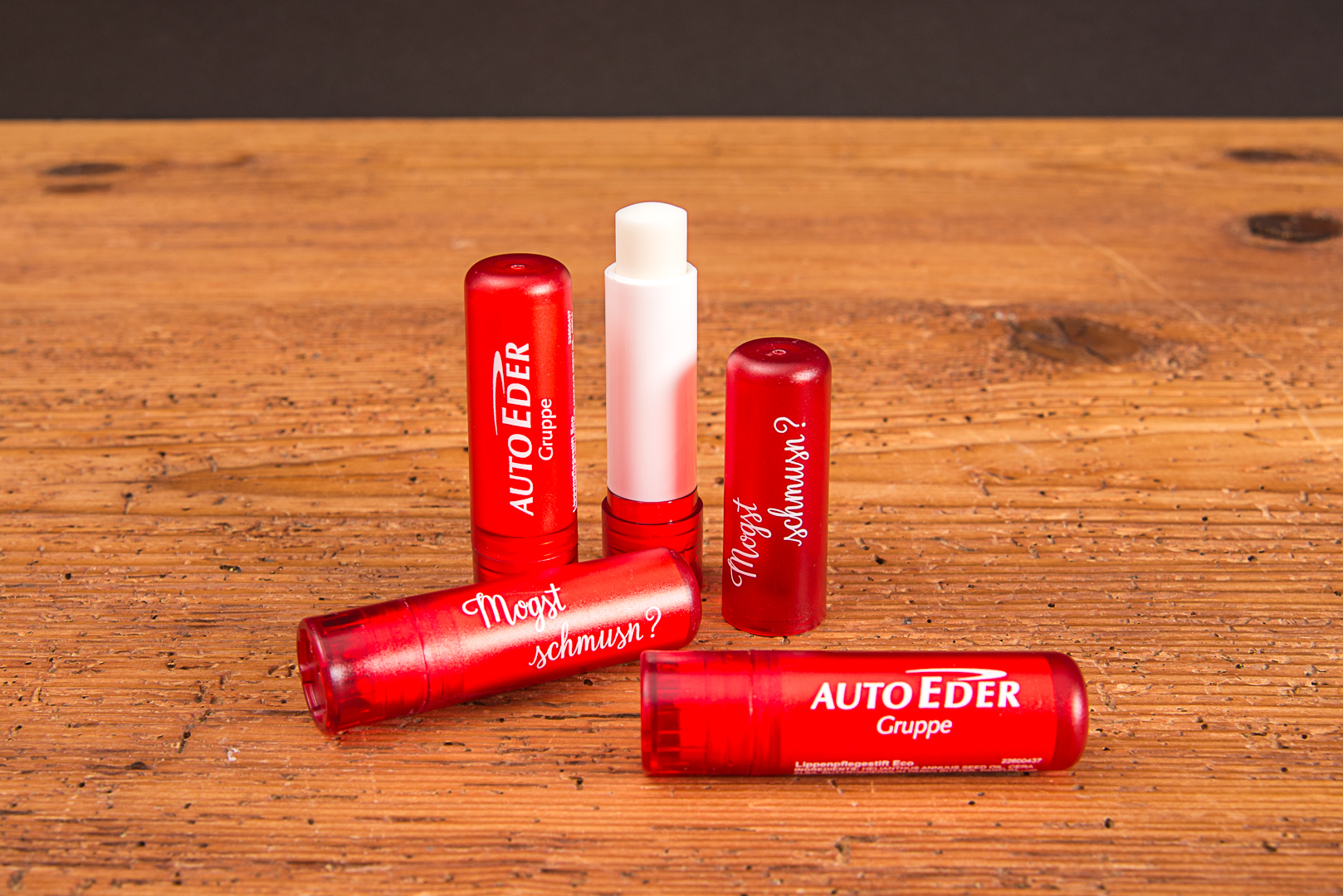 Rote Lippenpflegestifte VitaLip Eco mit individuellem Logo-Aufdruck auf Holzhintergrund