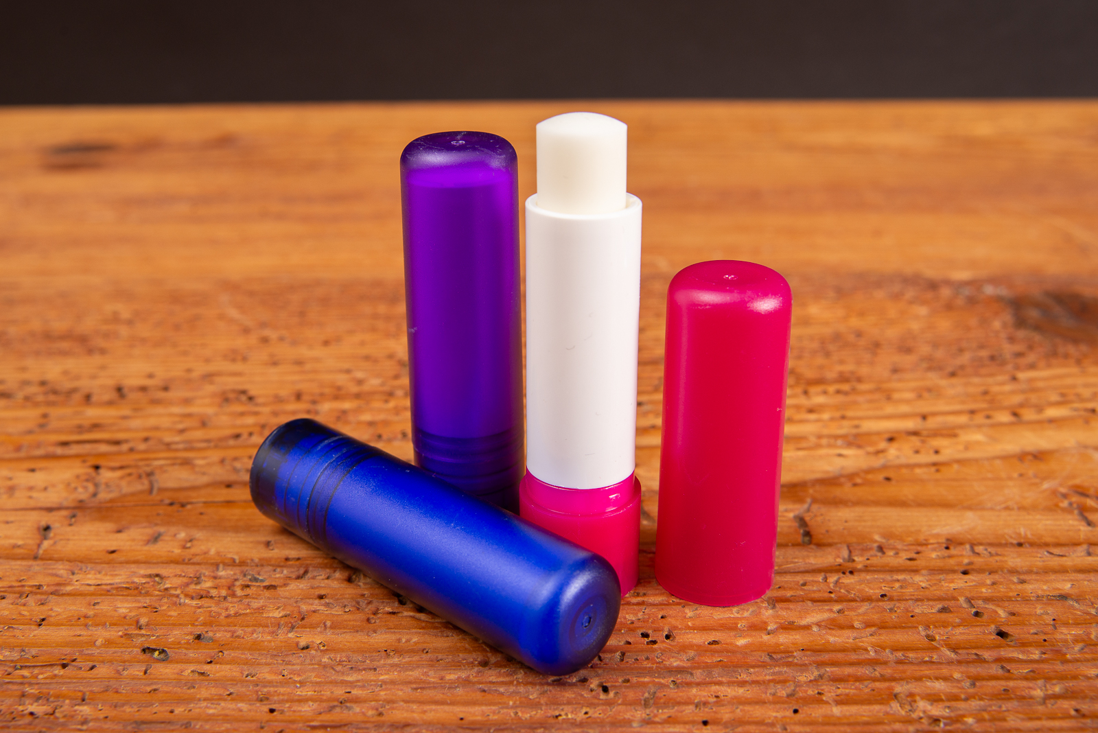 Ge&ouml;ffneter Lippenpflegestift mit wei&szlig;er Pflegemasse aus Sheabutter und Bienenwachs auf Holzgrund