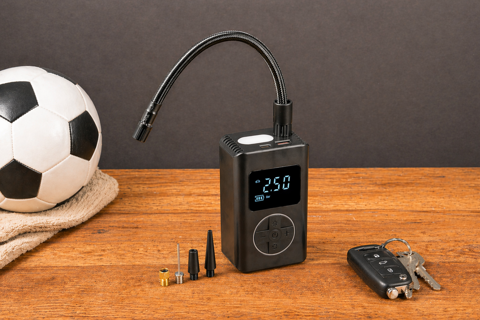 Elektrische PUMP Akkupumpe von werbemax mit Fu&szlig;ball, Ventil-Adaptern und Autoschl&uuml;ssel auf Holzuntergrund.