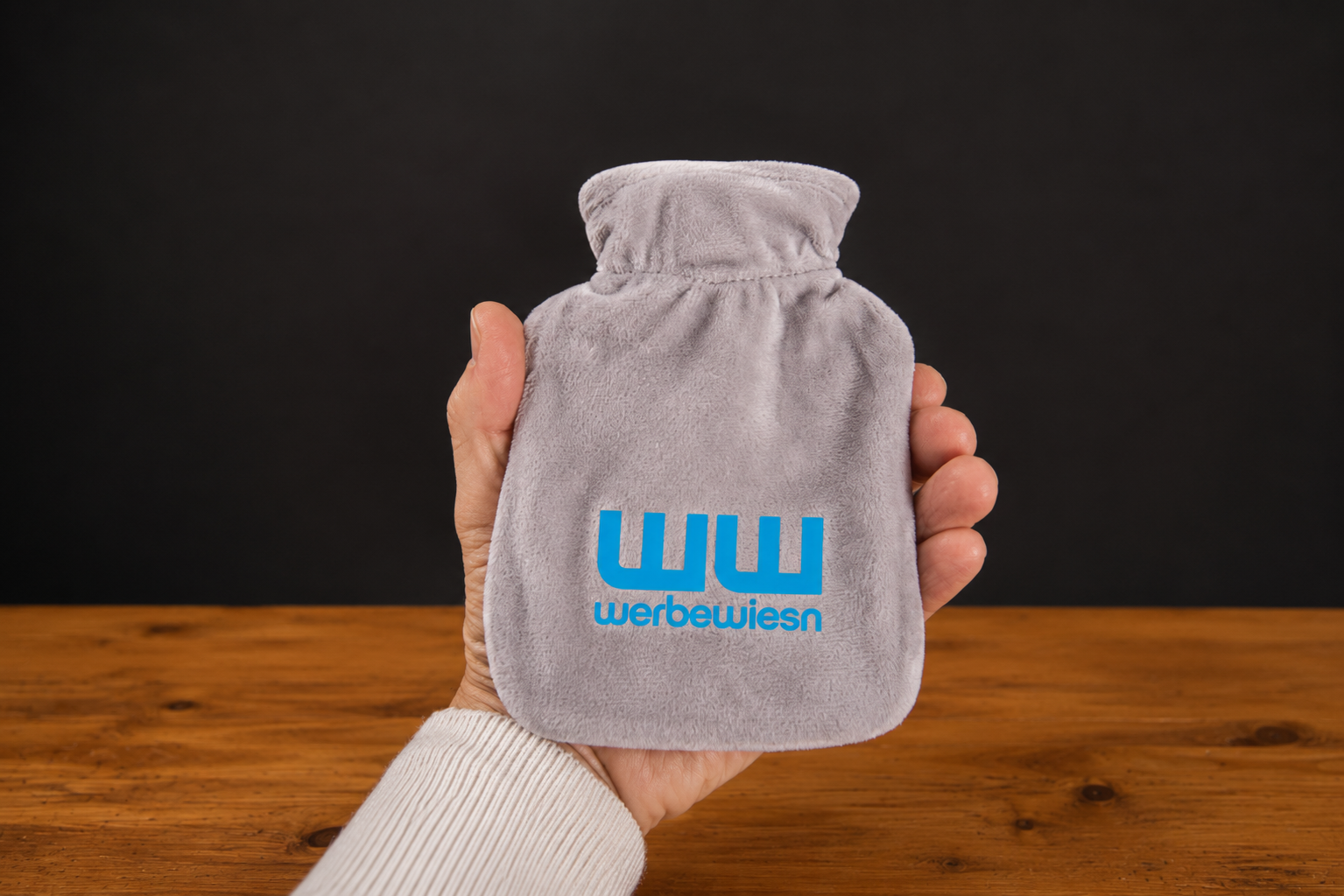 W&auml;rmflasche im Miniformat mit grauem Veloursbezug und blauem Logodruck.