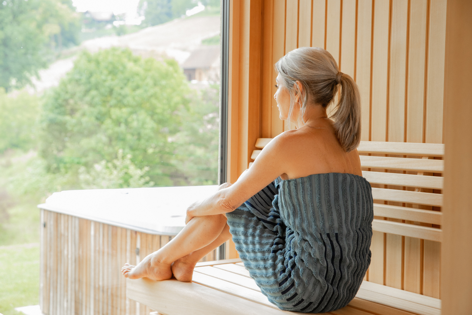 Frau sitzt in der Sauna mit Vossen Handtuch als hochwertiger Wellness Werbeartikel