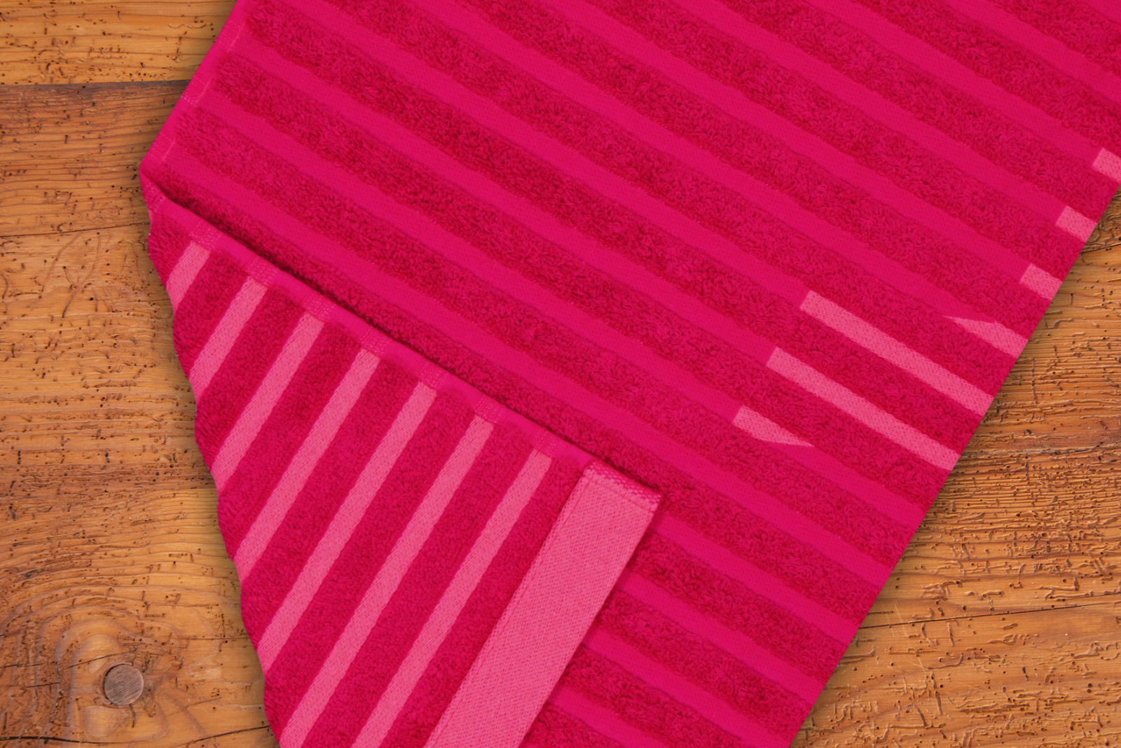 Rotes Vossen Saunatuch mit Streifenmuster auf Holztisch als hochwertiges Wellness Handtuch