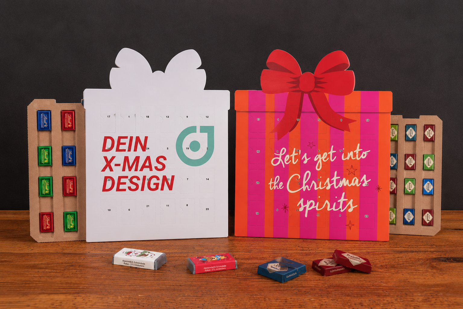 Zwei Geschenk-Adventskalender mit Schokolade von werbemax auf rustikalem Holztisch vor schwarzem Hintergrund &ndash; individuelle Weihnachtsdesigns mit Schleife, T&uuml;rchen und Marken-Schokolade.