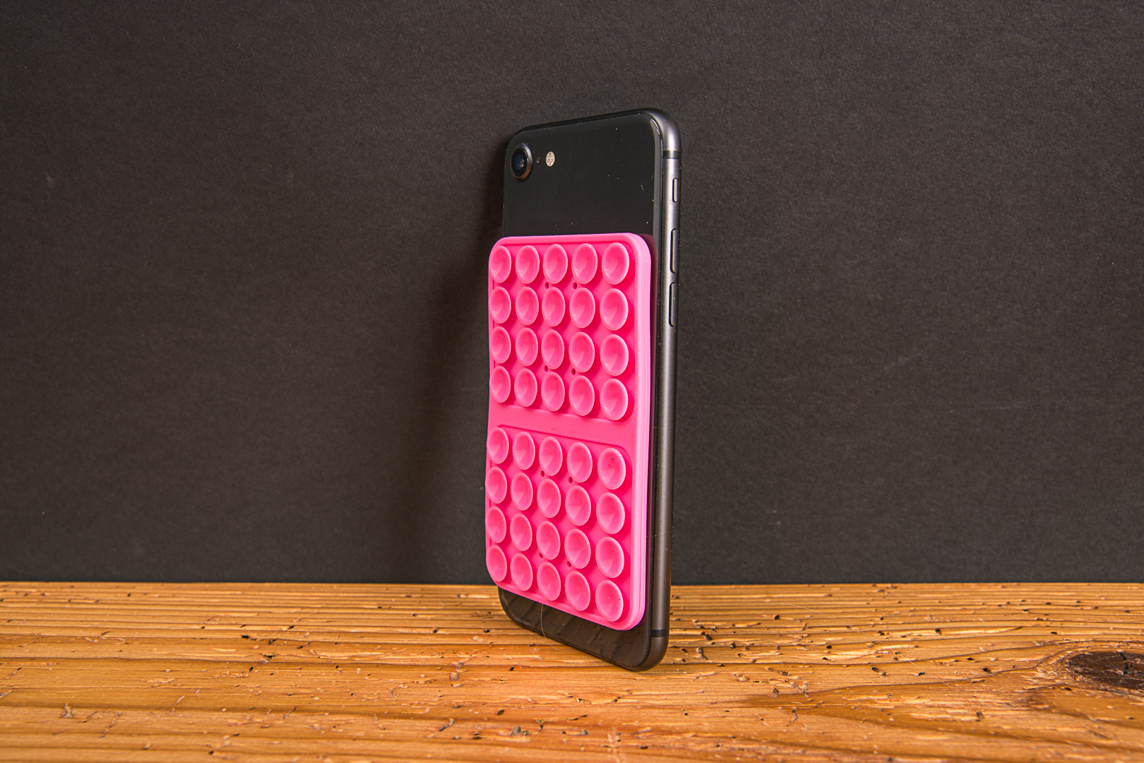 Seitenansicht einer flachen Silikon-Saugnapf-Halterung in Pink auf einem Smartphone. Platzsparendes Handy-Zubeh&ouml;r f&uuml;r Content Creator.