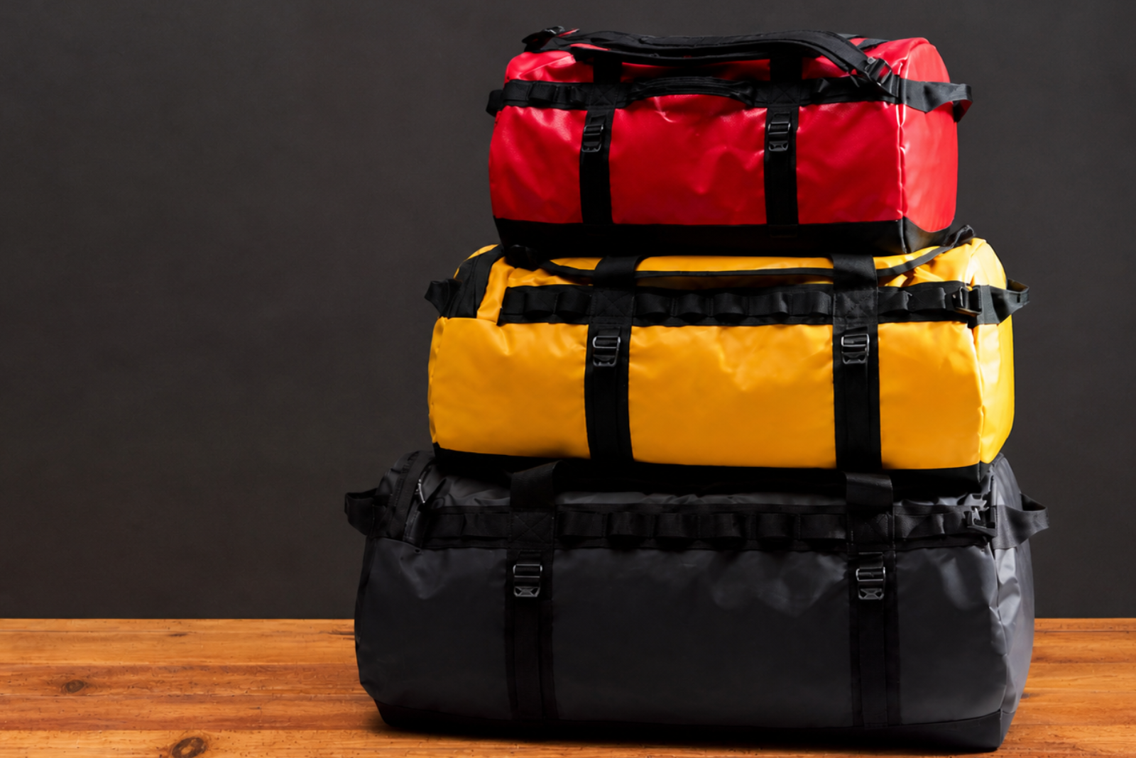 North Face Duffel Bags als hochwertige Werbeartikel mit Logo &ndash; stapelbare Outdoor Reisetaschen in Rot, Gelb und Schwarz f&uuml;r maximale Markenwirkung.