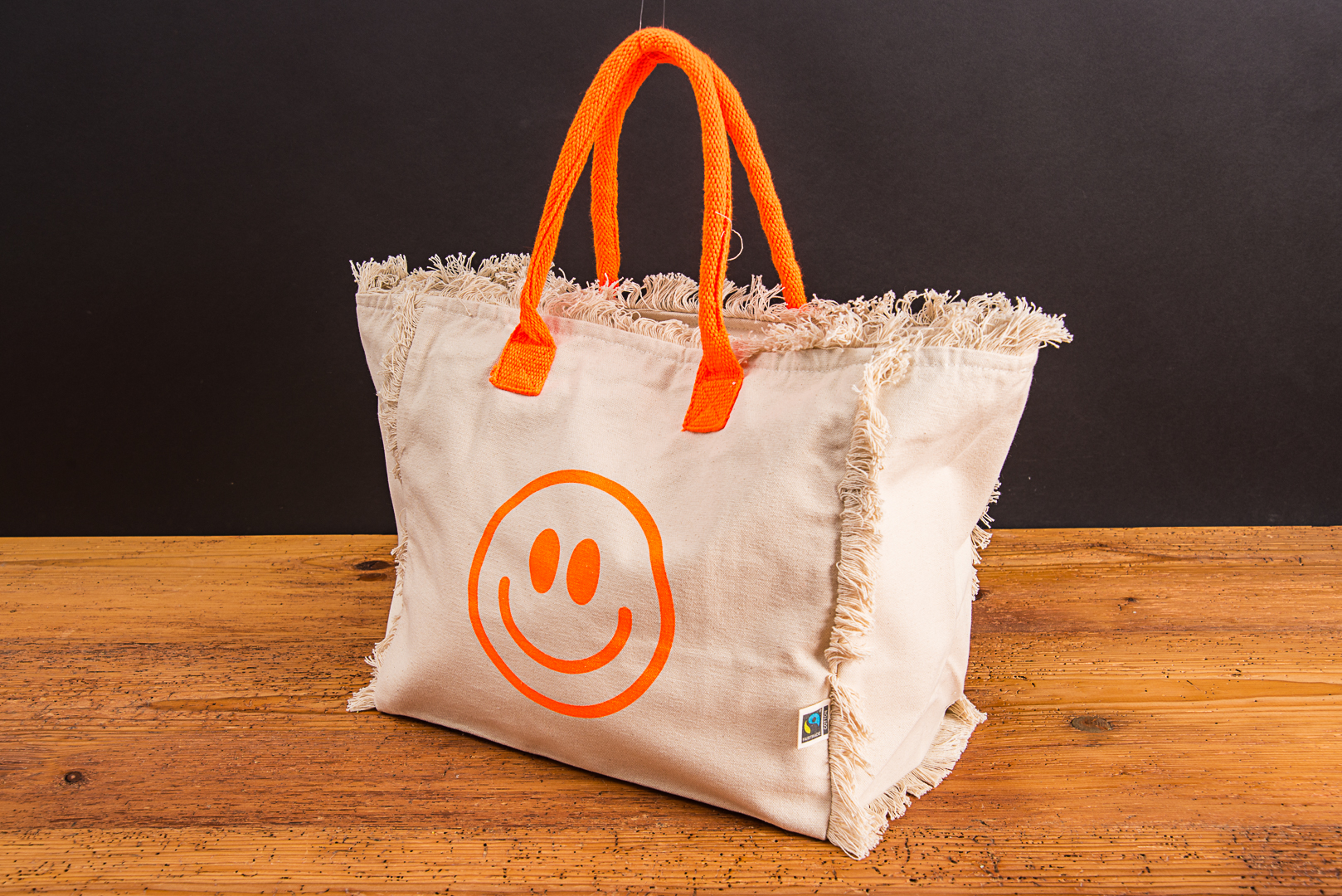 Strandtasche Lola mit Logo als sommerlicher Werbeartikel mit Smiley Design und farbigen Tragegriffen.