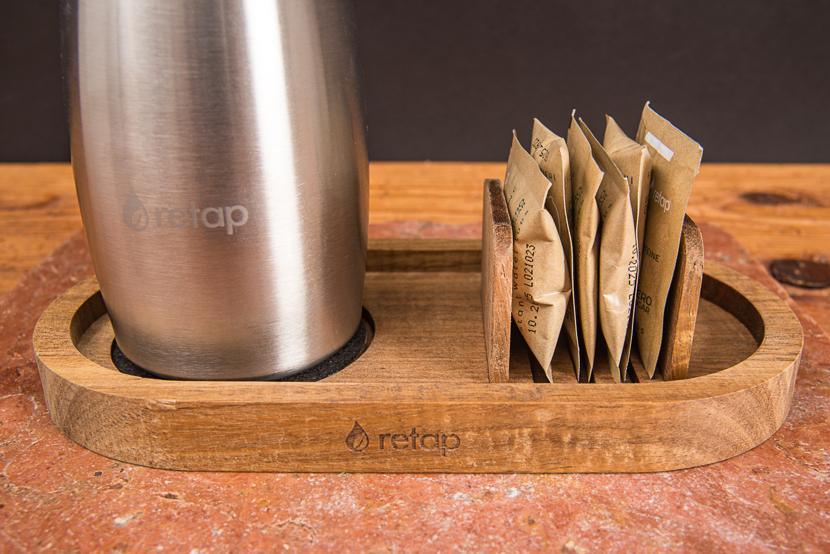 Detailansicht des retap Holztabletts aus Eiche mit eingesteckten Flavours und einer Edelstahlflasche als hochwertiges Willkommensgeschenk f&uuml;r Mitarbeiter von werbemax.