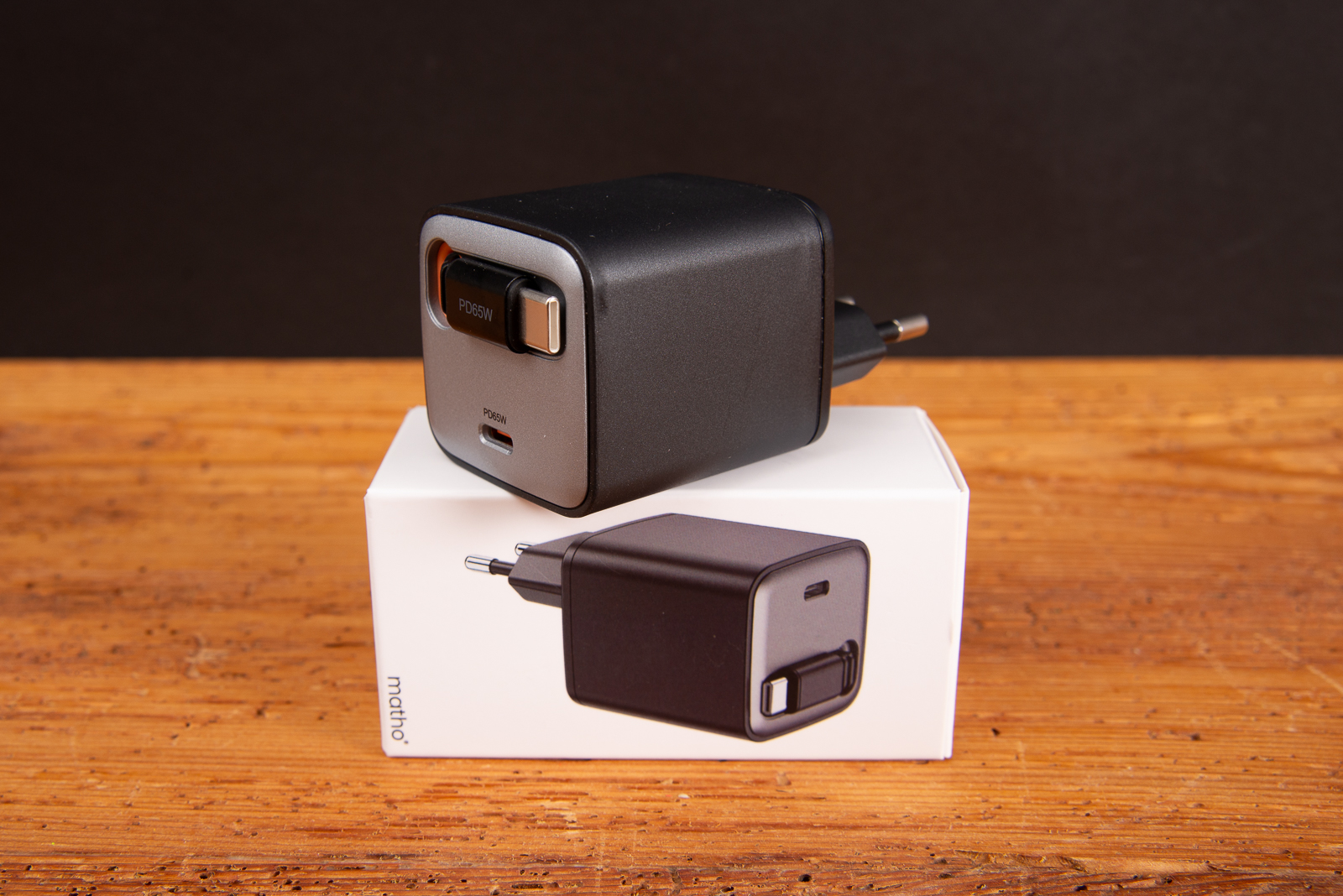 SUPPLY 65 C GaN Wandladeger&auml;t 65W platziert auf seiner wei&szlig;en Geschenkbox auf einem Holztisch vor dunklem Hintergrund