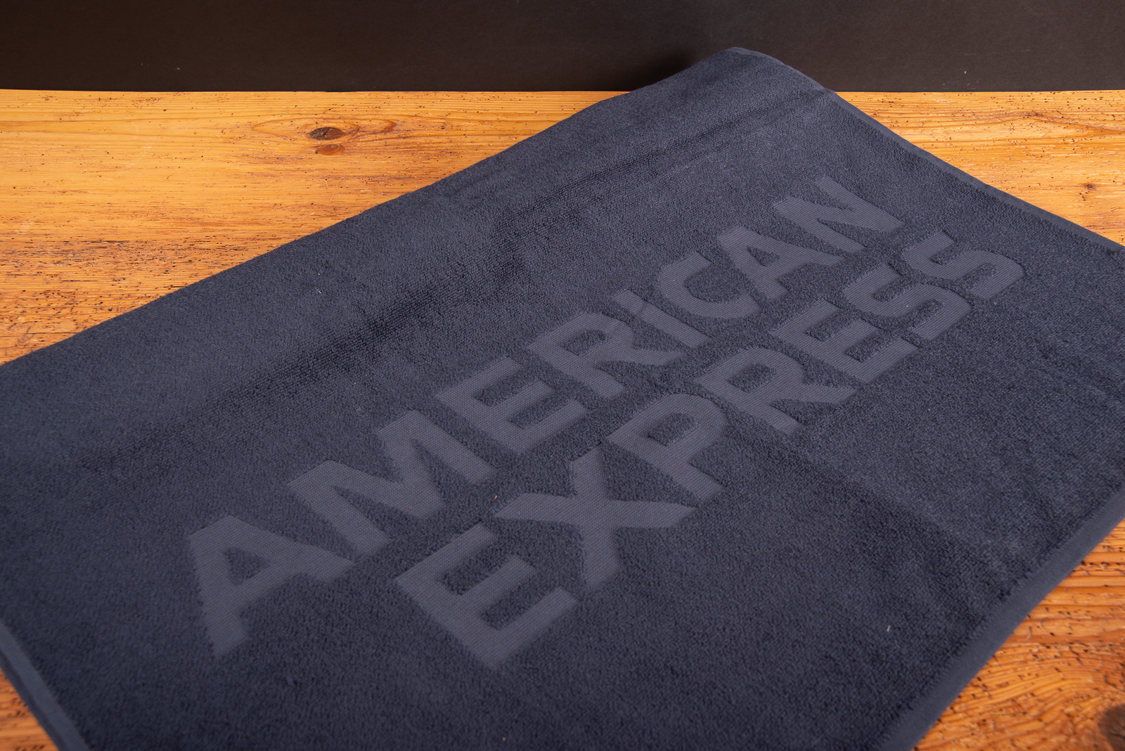 Individuelles Vossen Handtuch mit American Express Logo in Hoch-Tief-Einwebung.