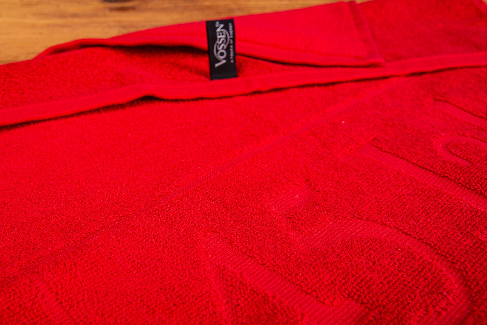 Rotes Vossen Handtuch mit individueller Reliefeinwebung und schwarzem Markenlabel.