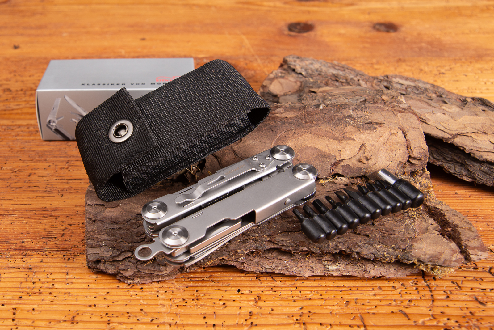 Richartz EXOTOOL 24+ Multitool mit Logo-Gravur, schwarzem Etui und Bit-Set auf Holz und Baumrinde