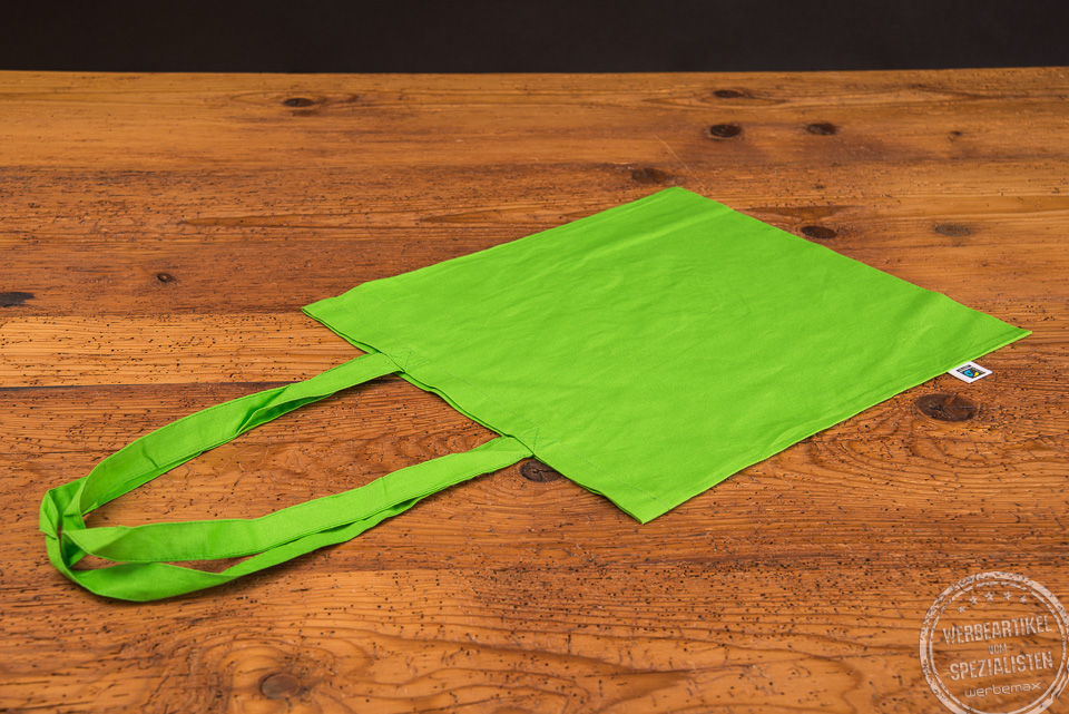 Baumwolltasche mit lanken Henkeln in der Farbe Grün mit Fairtrade-Label an der Seite
