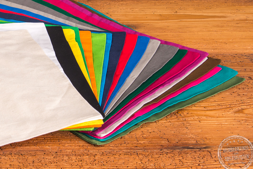 Nahaufnahme der aufgef&auml;cherten Messetasche in den 22 Standardfarben auf Holztisch als Standard Werbemittel 