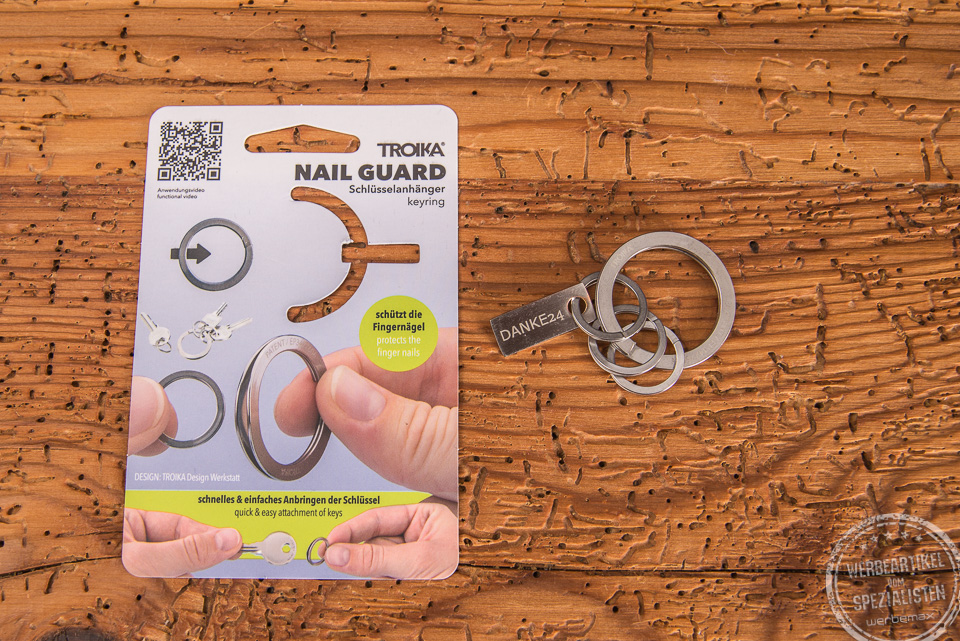 Troika Schlüsselanhänger Nail Guard liegend neben der Verpackung als Werbeartikel. 
