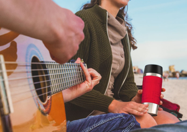 roter emsa travel mug thermobecher wird von Kunden auch in der Freizeit genutzt wie hier an Strand bei Gitarrenmusik.