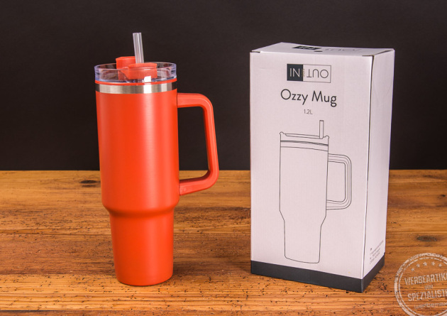 Trinkbecher Ozzy mit Strohhalm in Orange neben Kartonverpackung