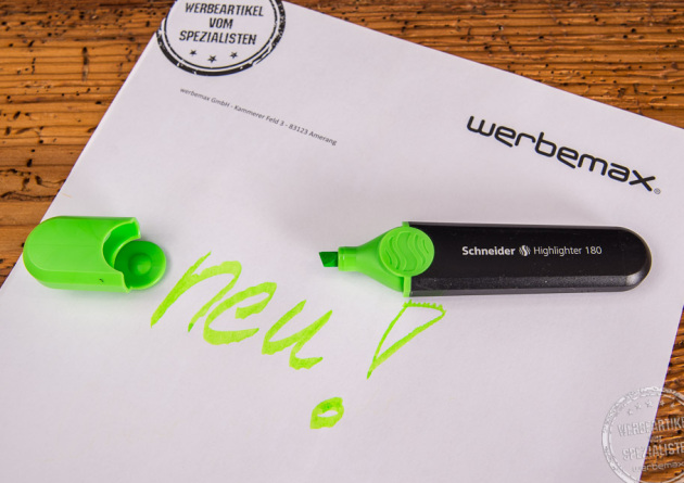 Textmarker von Schneider in Schwarz mit grüner Kappe. Auf weißem Blatt Papier steht das Wort "Neu" in grün