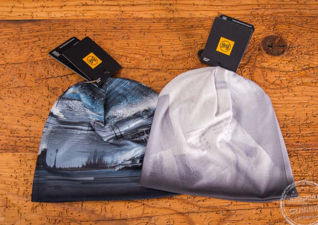 Zwei dünne Beanies von BUFF im 4c-Druck auf einem Holztisch gelegt mit dem original BUFF Label