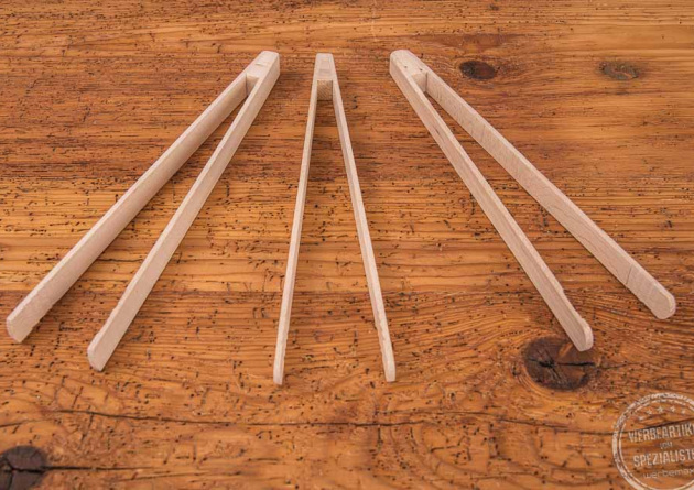 Drei Grillzangen aus Buchenholz als Werbegeschenk liegen nebeneinander auf einer Holztischplatte