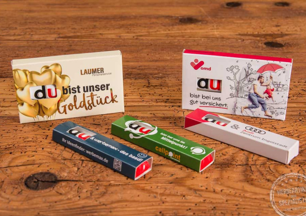 Verschiedene Duplo Schokoriegel in individuell bedruckten 1er- und 3er-Werbeschubern mit emotionalen Botschaften wie „Du bist unser Goldstück“ oder „Du bist bei uns gut versichert“ – kreative Werbeartikel für HR, Events und Marketingaktionen.