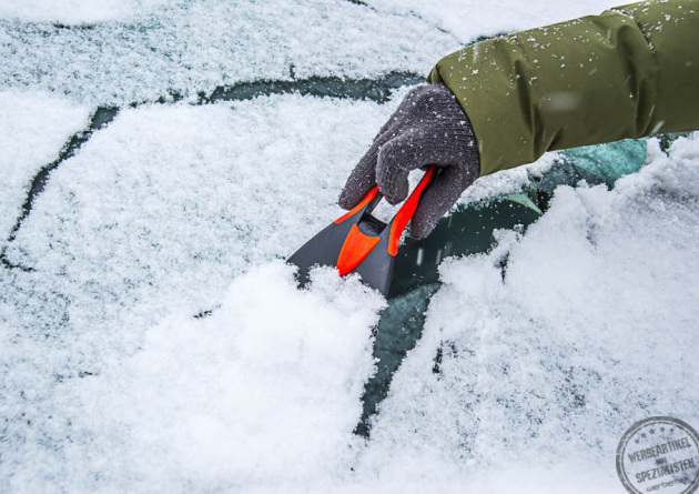 Eiskratzer entfernt Schnee von Autoscheibe