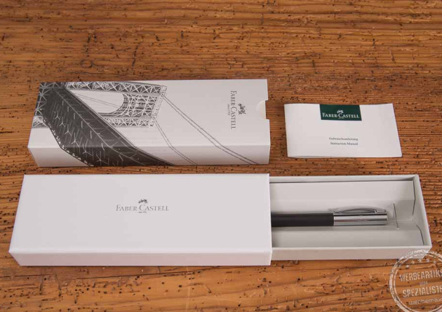 Faber Castell Ambition Kugelschreiber mit Gravur in stilvoller Werbegeschenke Verpackung als hochwertiges Kundengeschenk pr&auml;sentiert auf Holztisch.