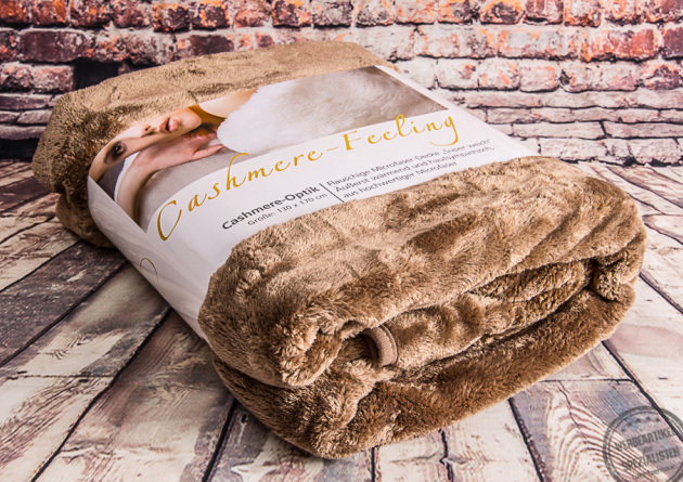 Cashmere Feeling Kuscheldecke braun mit Original Banderole auf Holzboden.