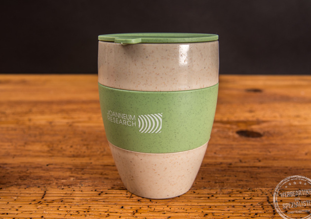 Thermos Kaffeebecher Aroma to go mit grünem Deckel und grüner Manschette als Werbeartikel.