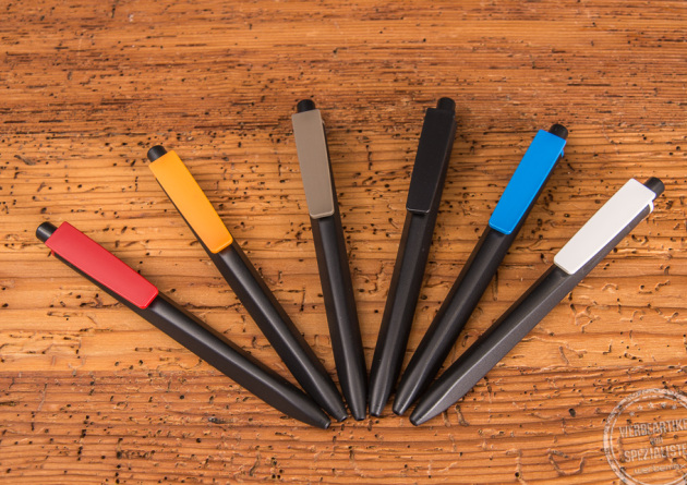Sechs Ritter Pen Kugelschreiber Ridge Recycelt in schwarz mit unterschiedlichen Schaftfarben liegend auf Holzfläche. 