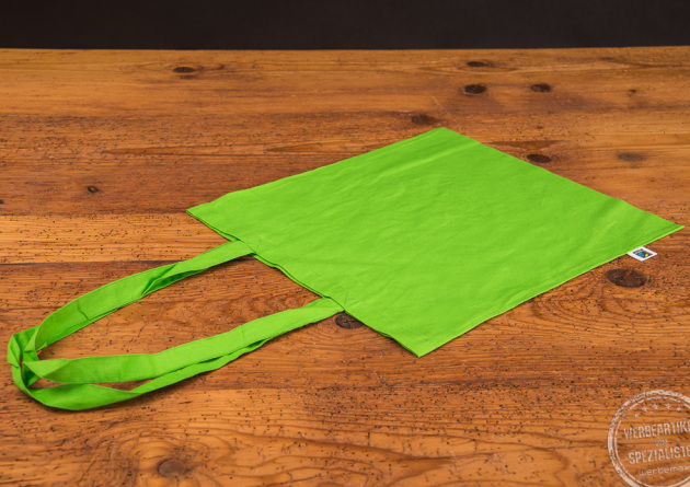 Baumwolltasche mit lanken Henkeln in der Farbe Gr&uuml;n mit Fairtrade-Label an der Seite