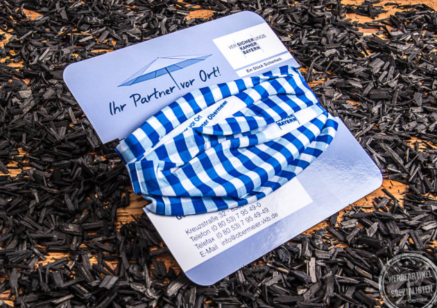 Multifunktionstuch Versicherungskammer Bayern auf einem Kartonheader aufgezogen