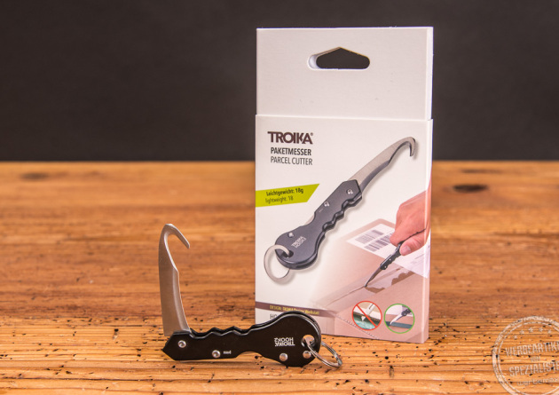 Troika Paketmesser Hook2 geöffnet liegend vor der Verpackung. 