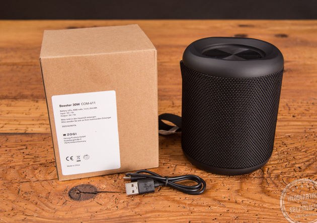 Rückseite der Kartonverpackung des schwarzen Bluetoothspeakers. Zudem sieht man das mitglieferte Zubehör, ein USB-C Ladekabel