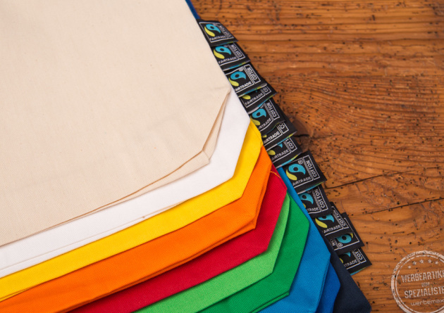 Detailaufnahme der nachhaltigen Baumwolltasche Edda mit Fairtradelabel an der Seite auf Holztisch.