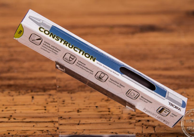 Construction Pen von Troika in Standardverpackung mit Beschreibung auf Holztischplatte.