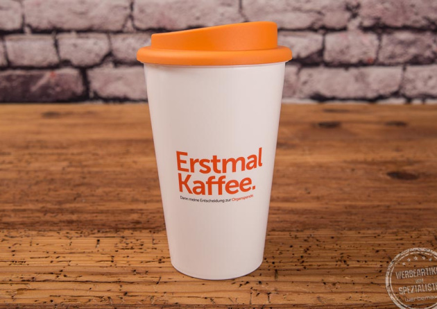 weißer Kaffeebecher mit Spruch und orangefarbenen Deckel